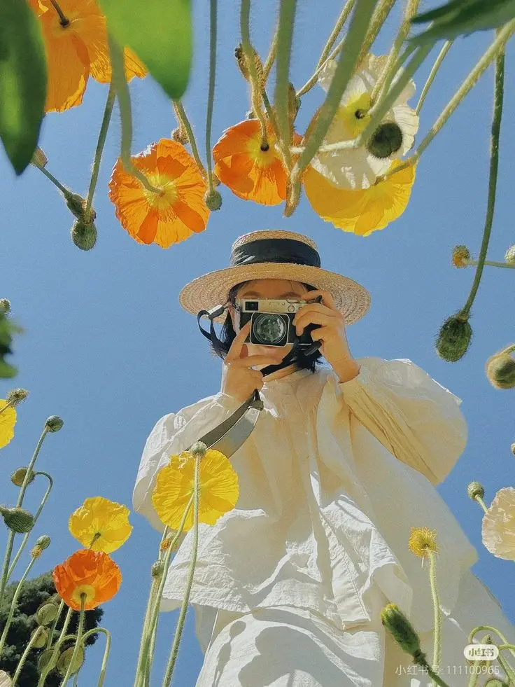 Persona con sombrero de paja fotografiando entre flores